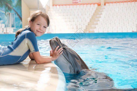 女孩与瓶鼻海豚在蓝水中游泳图片