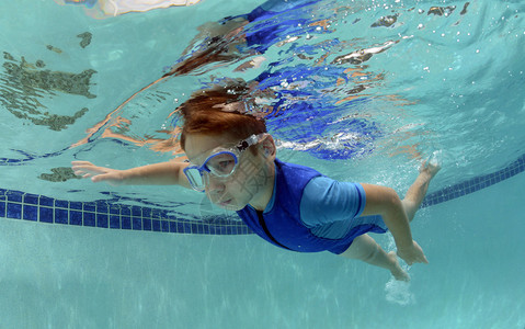 孩子在游泳池里屏住呼吸在水下游泳图片