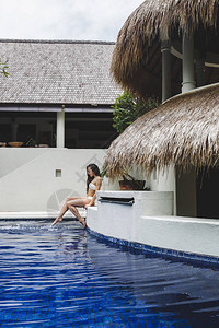 在热带度假胜地与深蓝水一起在游泳池附近度假的妇女图片