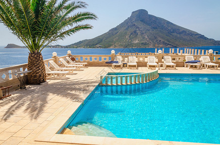 希腊的游泳池区和棕榈树下的日光浴床享有迷人的景色图片