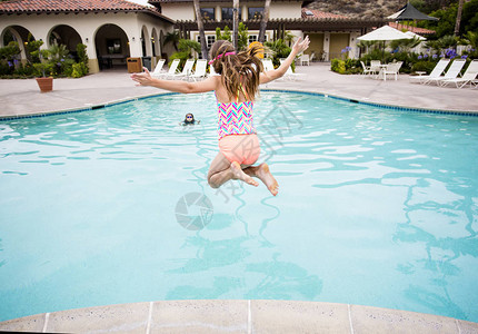 女孩跳进一个大后院游泳池图片