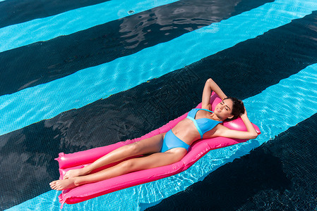 穿着比基尼的年轻女子躺在游泳池中粉红图片