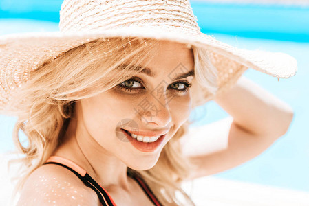 美丽的金发年轻女子的肖像穿着维杰帽在泳池附近图片