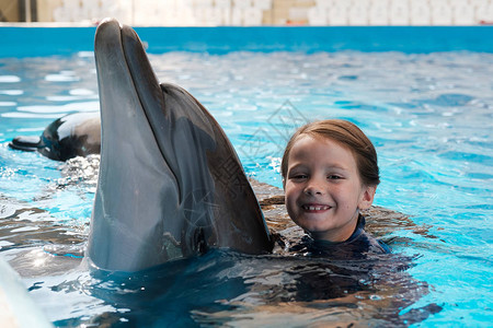 KidandDolphin女孩在蓝水中与瓶鼻海豚游泳并图片