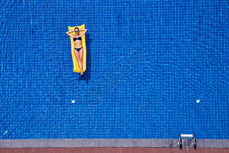 在大游泳池的黄色空气床垫上最能看清穿比基尼的瘦图片