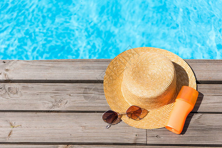 游泳池附近的雨帽太阳镜和防晒背景图片