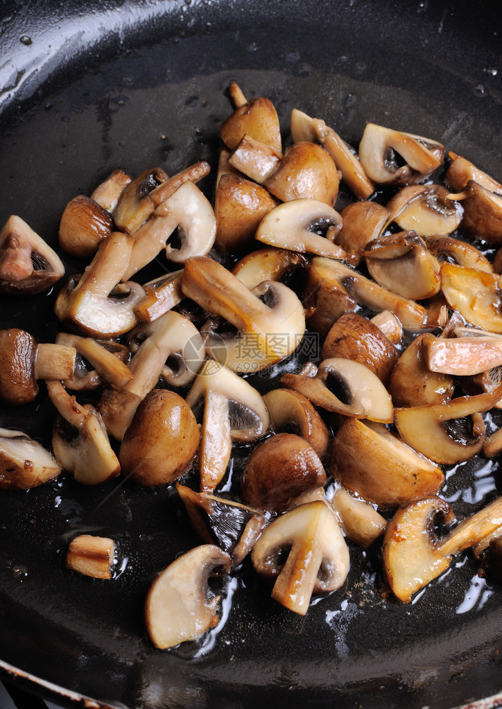 在煎锅中用黄油切成的炒蘑菇图片