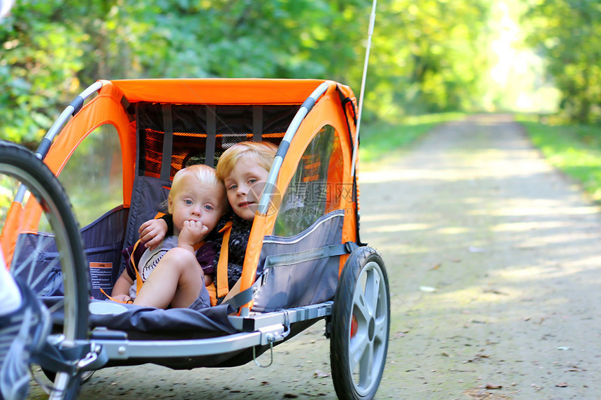 两个小孩坐在自行车拖后面的拉车里图片