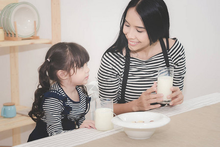 亚洲妈幸福的家庭早上和她可爱的女儿一起喝牛奶家庭孩子和快乐的人概图片