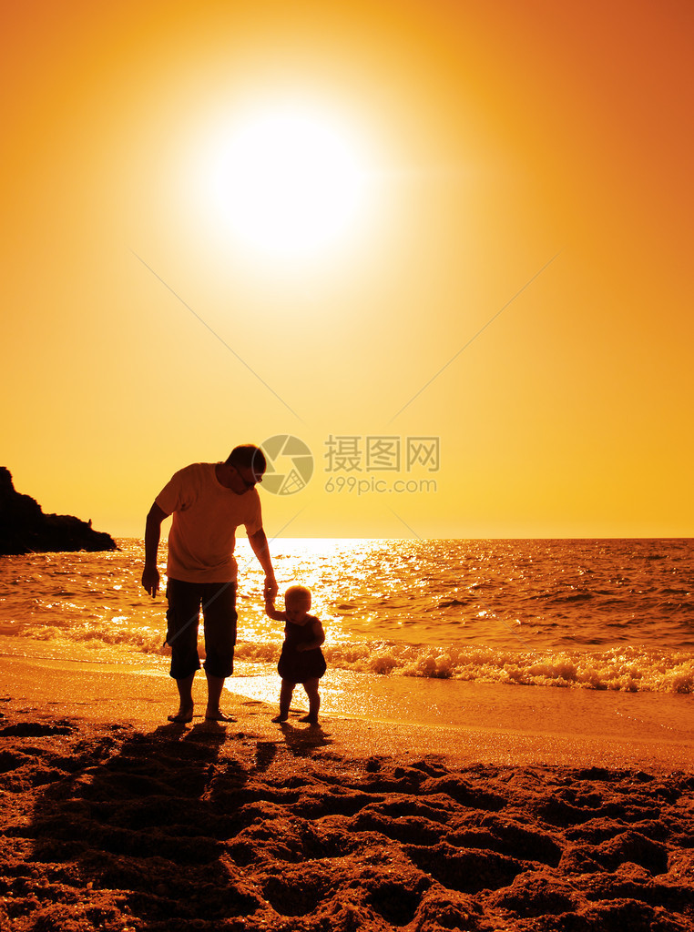 日落时在沙滩上玩耍的父女图片