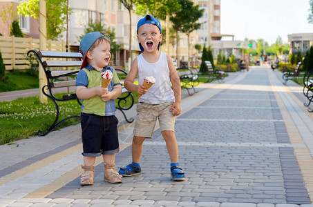 两个身穿帽子的男孩夏天在街上吃冰淇淋甜图片