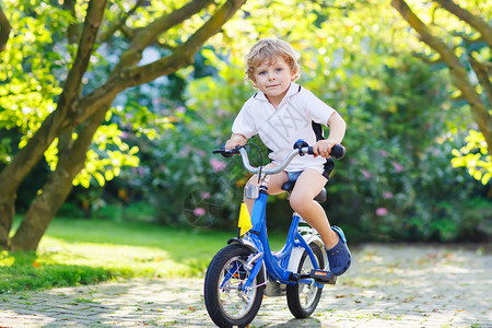 可爱的孩子在温暖的夏日骑着第一辆自图片