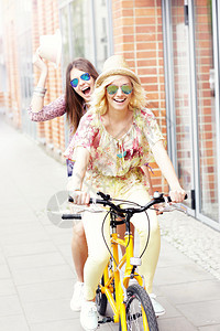 一张两个女孩朋友在城市骑自行车的照片图片