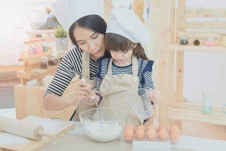 厨房里的幸福家庭亚洲母亲和她的女儿准备面团做蛋糕家庭孩子和快乐的人概图片