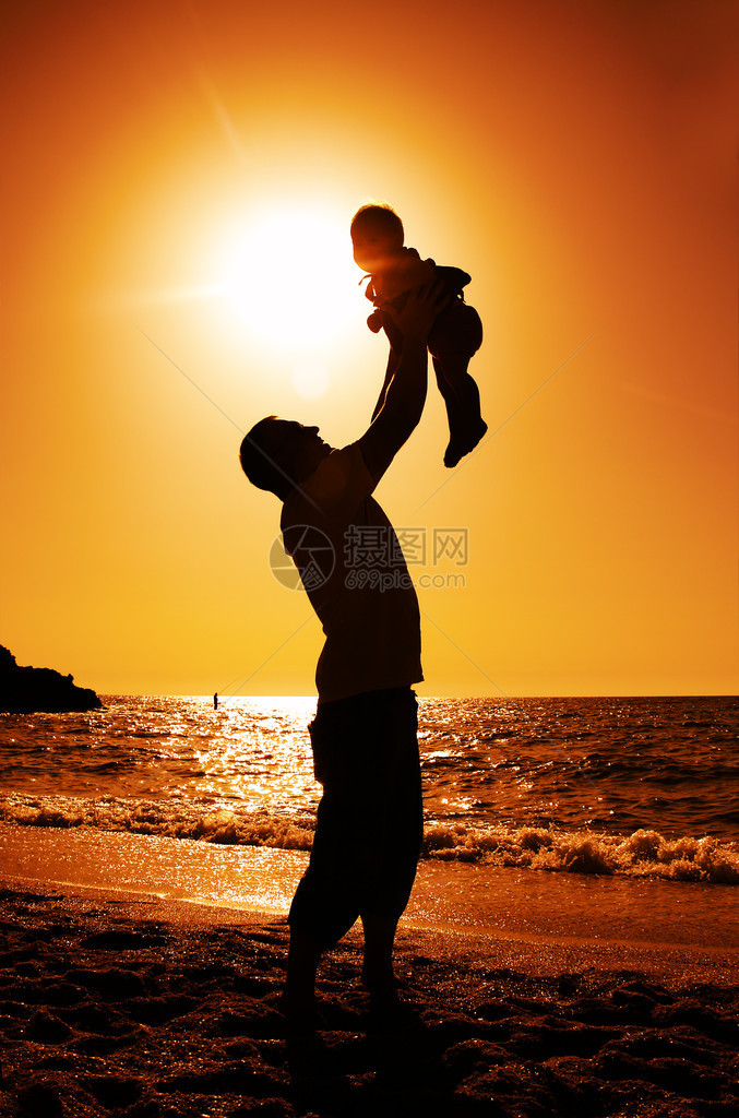 日落时在沙滩上玩耍的父女图片