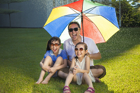 父亲和两个女儿坐在草地上图片