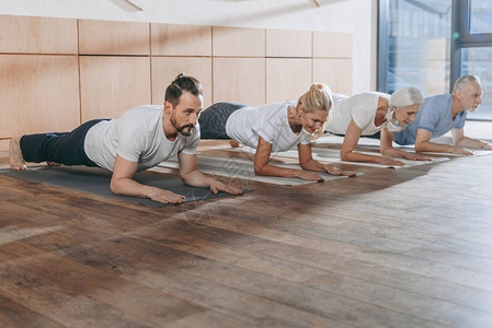 一群人在工作室的瑜伽垫上做木板背景图片