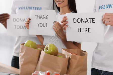 手持带有一袋苹果的慈善标牌的志愿者图片