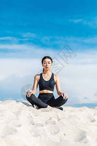 在莲花瑜伽中冥想的亚洲女摆在沙上对图片