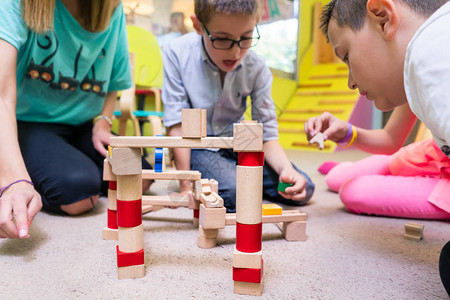 专职幼儿园教师在有监督的空闲时间帮助儿童建造木制火车图片