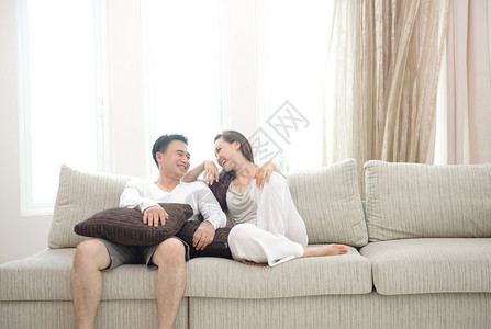 坐在沙发上欢乐的亚裔情侣享受图片