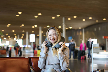 欧洲年轻女坐在机场候机室的领头枕和售货券上出国旅行和欢图片