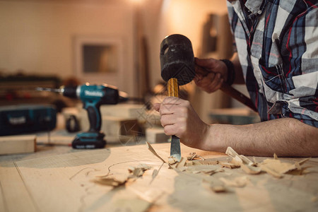 木匠在车间用凿子和锤子工作背景图片