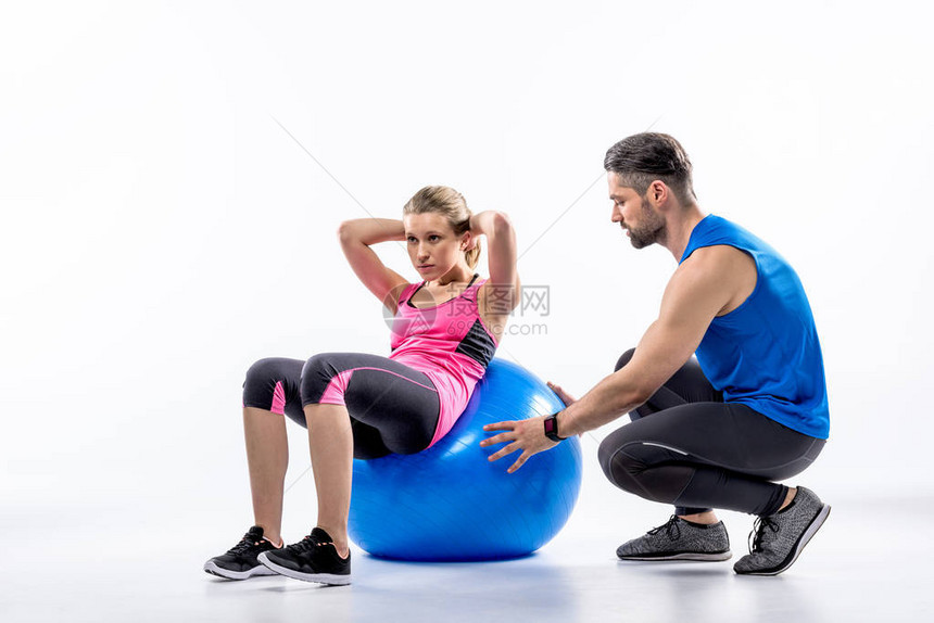 女在健身球上做腹肌训练与她的教图片