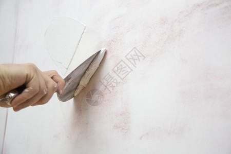 房屋改善用抹刀把石膏贴在墙上图片