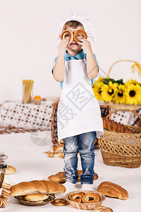 小男孩厨师穿着白色厨师制服在厨房做饭时微图片