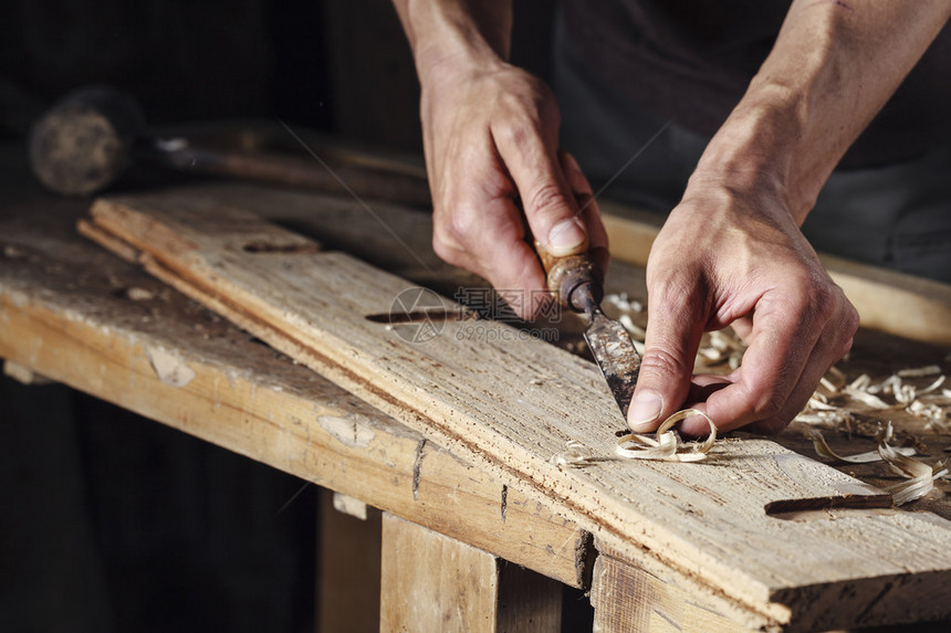 在木制工作台上用锯子和雕刻工具操作木制图片