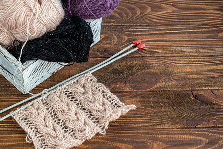 手工制作的木制背景上的金属织针和羊毛线在家织毛衣爱图片