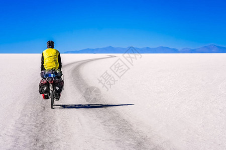 孤独的男骑自行车者穿越世界上最大的盐沼图片