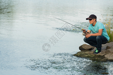 有人在河边钓到一条鱼带着眼镜和帽图片