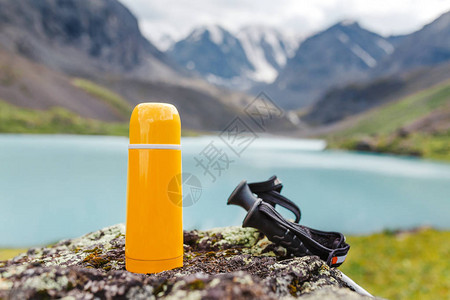 湖边石头上的保温瓶和登山杖图片