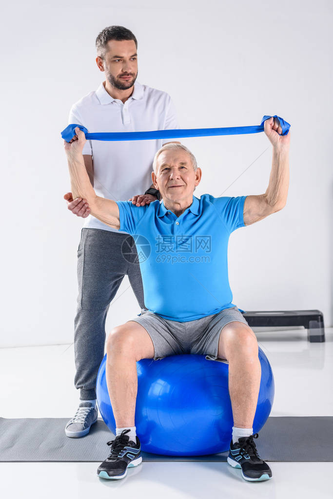 康复治疗师协助老年男子在健身舞会上用橡胶图片