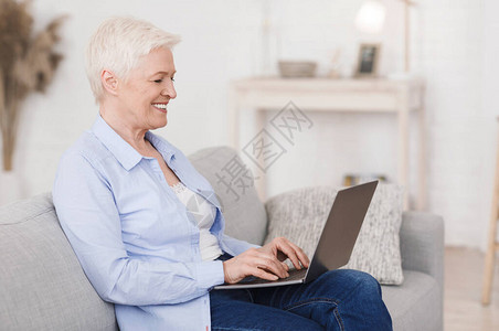 年长者约会场所在家使用笔记本电脑键盘打字微笑有选择的焦点侧视等快乐的图片