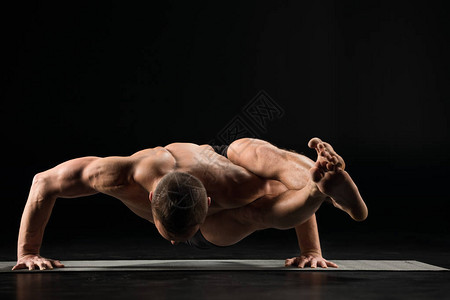 做瑜伽的年轻男子在被隔离在黑边的瑜伽垫上做一个阿萨娜阿斯图片