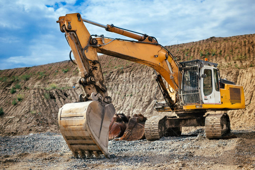 从公路建筑工地装载土壤材料的工业重型挖土机图片