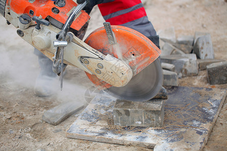 切割混凝土瓷砖沥青或混凝土切割机和工人靴建筑工人使用混凝土锯图片