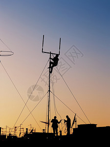 3名工人修补屋顶上通讯天线的休整月光日落时电图片