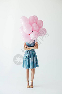 模糊的眼神女人与手臂交叉和一堆粉色气球背景图片