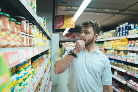 一个男人想在超市里选择什么样的产品买家在商店挑选罐头食品图片