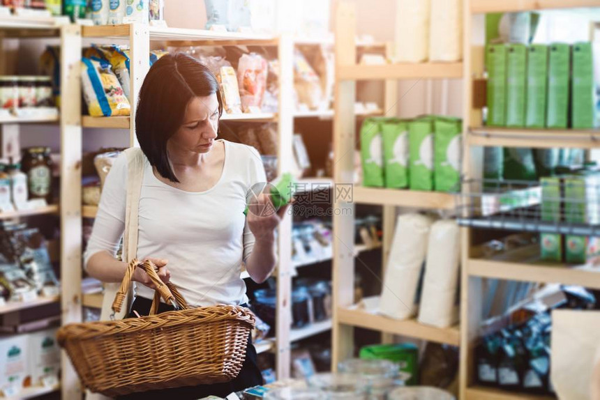 女人在商店选择健康食品并阅读标签图片