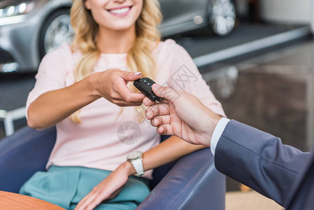 售卖者给汽车钥匙在汽车沙龙中微笑的女人的图片