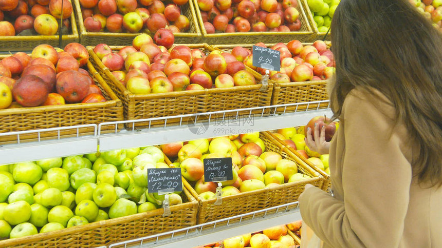 妇女在杂货店生产部挑选新鲜红苹果并将其放入塑料袋中年轻漂亮的女孩正在超市里挑选苹果并将它们放入图片