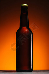 橙色背景下啤酒瓶的特写视图图片