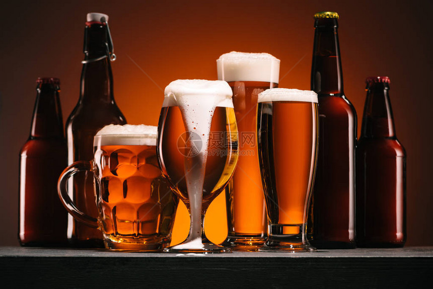 橙色背景下啤酒瓶和大杯的特写视图图片