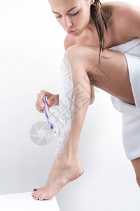 清晨淋浴后刮腿毛的有重点的妇女在白色图片