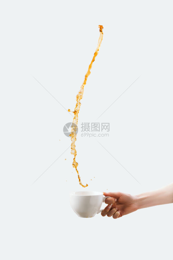 手握杯子的局部视图夹着热泼溅咖啡图片